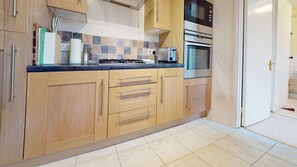 A kitchen with wooden cabinets, a gas stove, a microwave, and an oven. - Mill House | Oxford Holiday Let | 2 Beds & Sleeps 4 (Oxford)