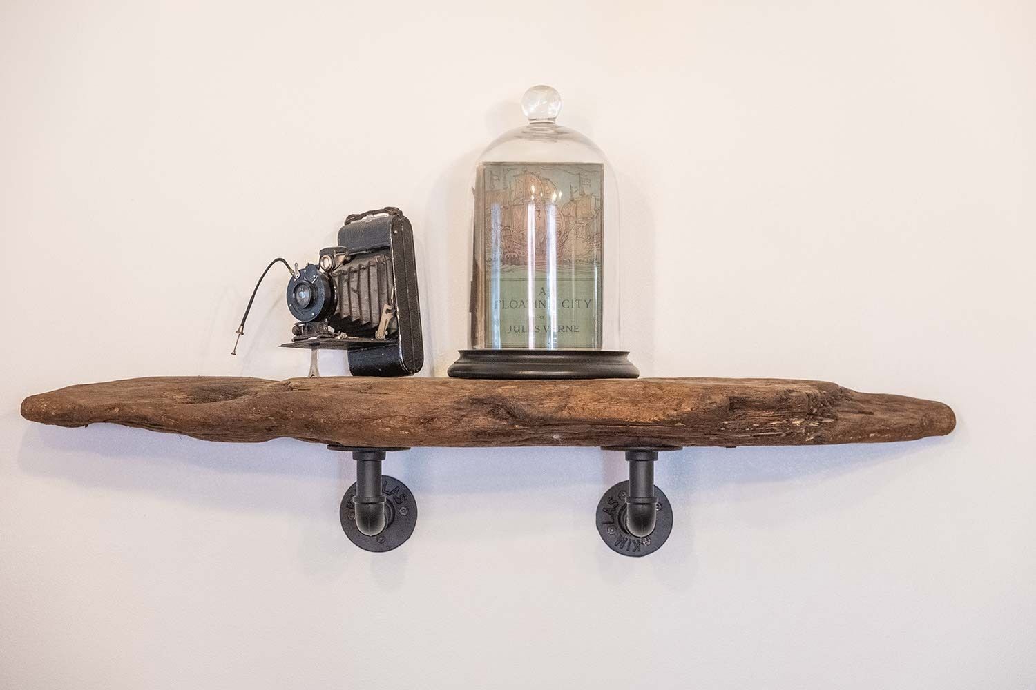 A wooden shelf with a vintage camera and a glass dome containing a map.