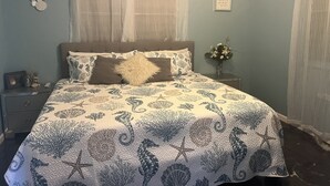 A bedroom with a bed, a nightstand, a vase with flowers, and a wall with a framed quote. - Peaceful, fully renovated home that is solar powered!   (Rincon)