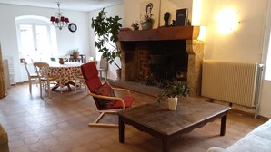 A living room with a fireplace, a dining table with chairs, and a sofa. - Grande Ourse guest room (SEMBADEL)