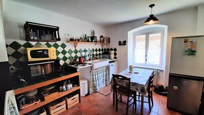 A compact kitchen with a microwave, stove, and sink. There's a small dining table with chairs and a window providing natural light. - Grande Ourse guest room (SEMBADEL)