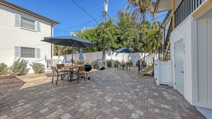 A patio with a brick floor, outdoor furniture, and a covered grill area.