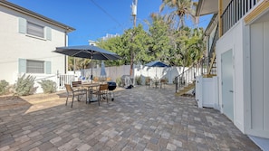 Un patio con suelo de ladrillo, mobiliario exterior y una parrilla cubierta.