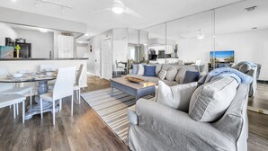 Una sala moderna con un sofá gris, una mesa de centro y un comedor con sillas blancas.