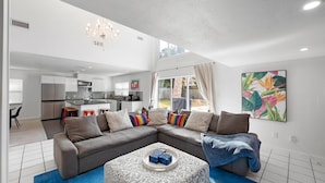 Una sala de estar moderna con un sofá modular, una mesa de centro y una cocina al fondo.