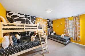 Ein Zimmer mit zwei Etagenbetten, einer Stehleiter und einem kleinen Schreibtisch.