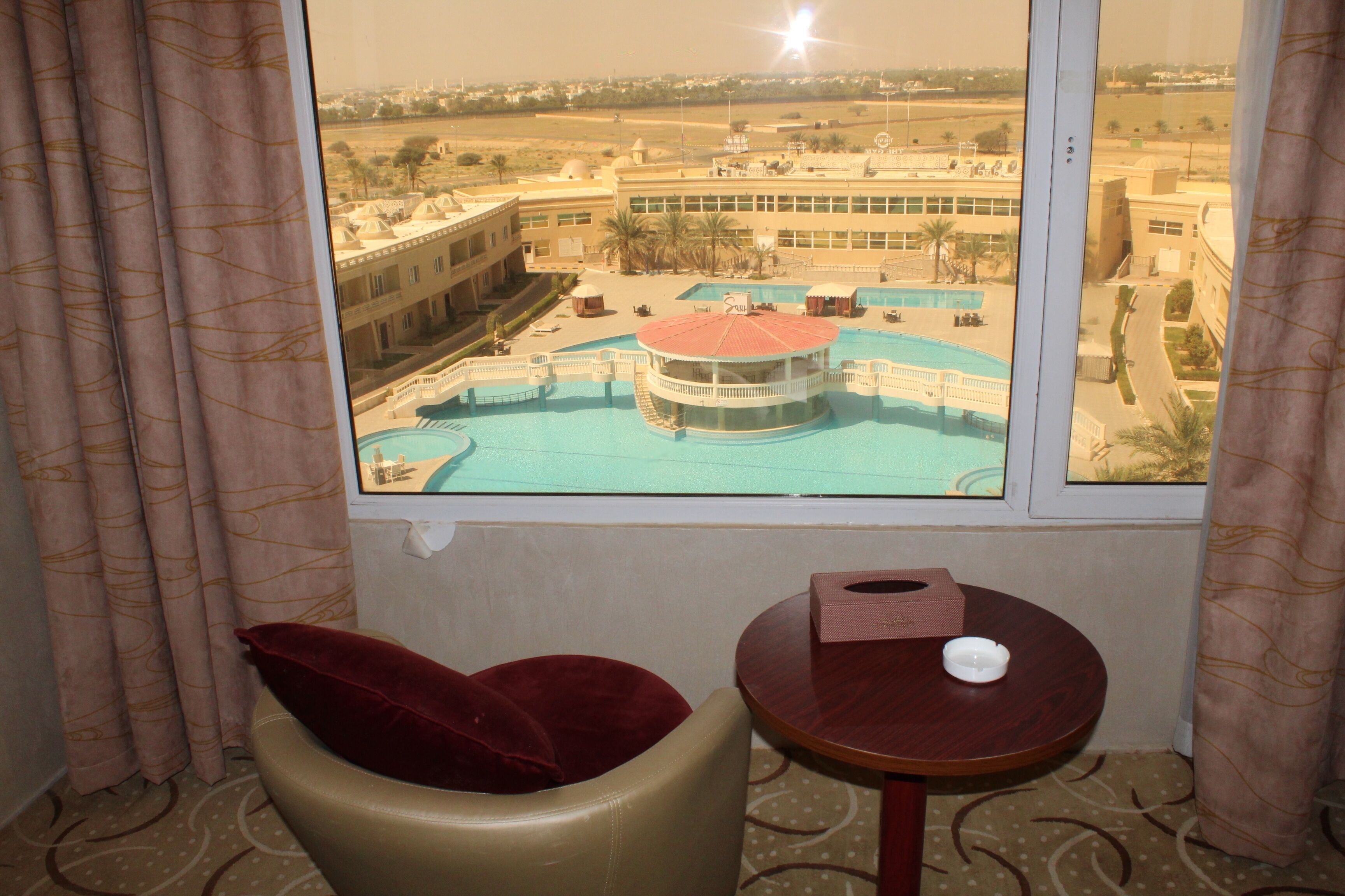 Ein Hotelzimmer mit Blick auf einen Swimmingpool und einen Gebäudekomplex.