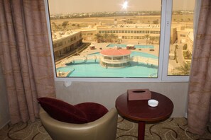 A hotel room with a view of a swimming pool and a building complex. - Al Salam Grand Hotel & Resort (Al Buraymi)