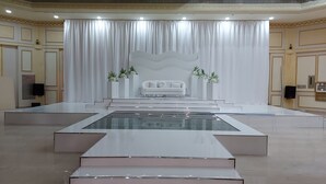 A spacious, modern hotel lobby with a central stage, white curtains, and a white sofa. - Al Salam Grand Hotel & Resort (Al Buraymi)