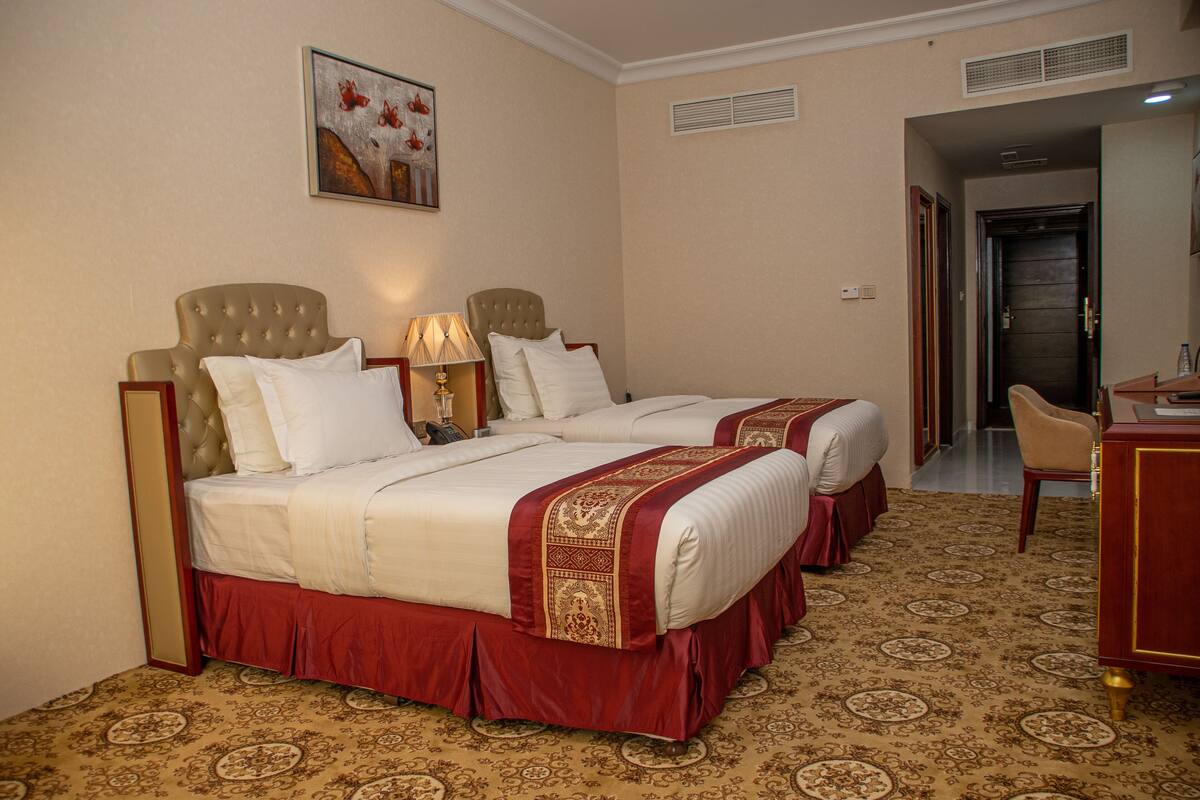 A hotel room with two beds, a desk, and a chair.