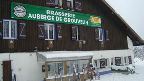 Ein Gebäude mit einem Schild für 'Brasserie Auberge de Grouvelin' und einer Reihe von Skiern davor.