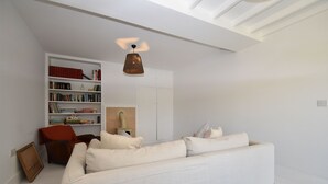 Een moderne woonkamer met een witte bank, een boekenkast en een hanglamp.