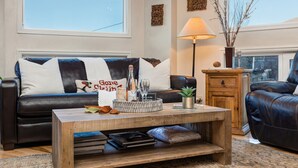 A living room with a dark leather sofa, a wooden coffee table, and a lamp. - Park City Ski Trip - Lift Line Condo Hot Tub (Park City)