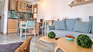Une cuisine moderne avec des meubles en bois, un coin repas doté d’un canapé bleu et une petite table agrémentée de plantes décoratives.