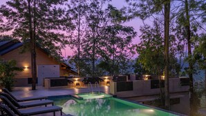 Un área de piscina moderna al aire libre con sillones de descanso, una piscina y un edificio de techo inclinado.