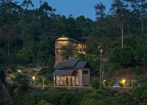 A two-story house with a large balcony, surrounded by dense forest. - Tea Terrain Resorts & Spa (Peermade)