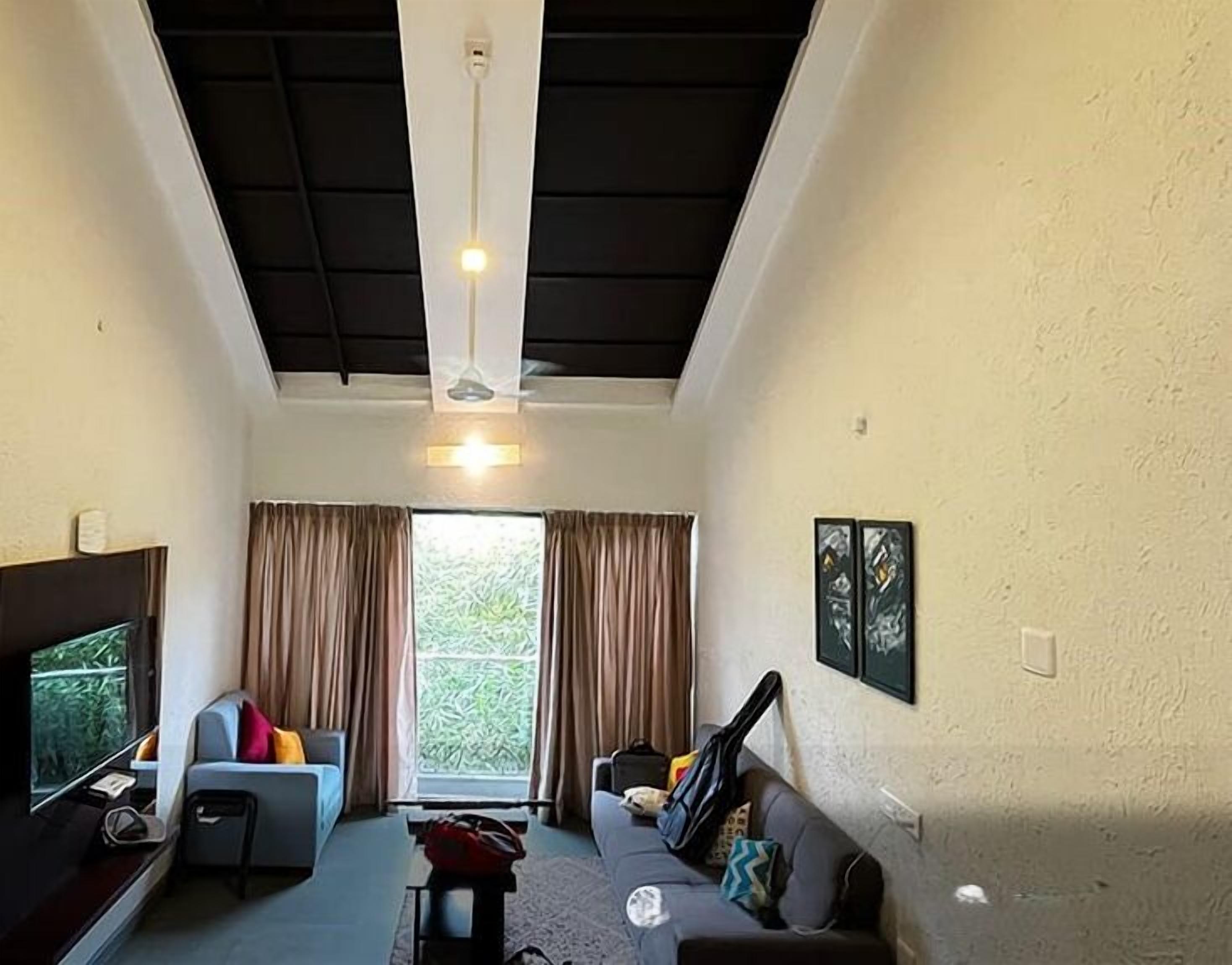 Un salón con sofá, una mesa de centro, televisor y un ventanal con cortinas.