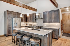 A modern kitchen with dark wood cabinets, stainless steel appliances, and a central island with stools. - Winter Park Resort Villa 401 I Private Hot Tub I Great Views I Bunk Room I Discounted Attractions (Winter Park)