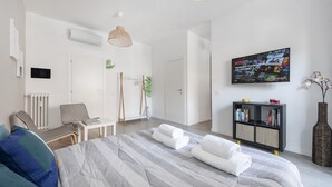 A modern hotel room with a large bed, a desk, a chair, a TV, and a bookshelf. - EasyStayRome | Vatican Home | Near Metro (Roma)