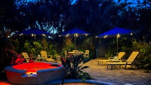 An outdoor pool area with lounge chairs and umbrellas, surrounded by tropical plants. - Tranquil Guest Suite in Paradise with Private Pool Walking Distance to Town
 (Saint Augustine)