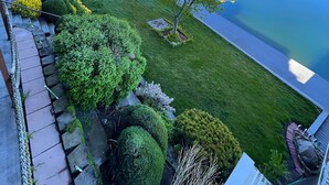 A landscaped garden with a view of a calm lake, stone pathways, and a wooden deck. - Lake Front home w/Dock & Boat Launch ✨ Closer to the Sun Lake House (Moses Lake)