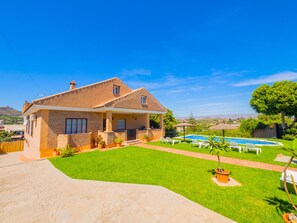 Ein zweistöckiges Haus mit Pool, gepflegtem Rasen und freiem Blick auf die umliegende Landschaft.