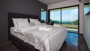 A modern bedroom with a large bed, a nightstand, a mirror, and a view of the outdoors. - Villa Tiara with Pool (Premantura)