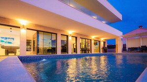 A modern building with a swimming pool, large glass doors, and a flat roof. - Villa Tiara with Pool (Premantura)