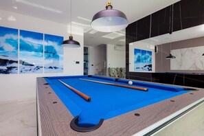 A pool table with a blue felt surface, two pool cues, and a white cue ball.
