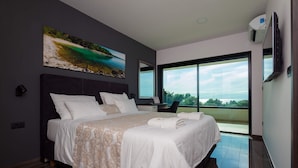 A modern hotel room with a large bed, a desk, and a view of the sea. - Villa Siena with Pool (Premantura)