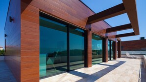 A modern building with large glass windows and a wooden exterior. - Villa Siena with Pool (Premantura)