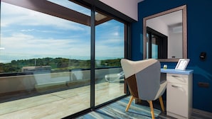 A modern room with a large sliding glass door leading to a balcony, a desk with a chair, a mirror, and a small cabinet. - Villa Siena with Pool (Premantura)