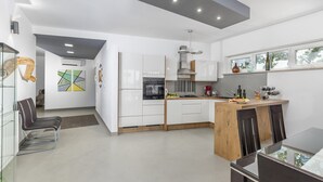 Una cocina moderna con armarios blancos, horno empotrado y una isla de madera.