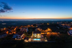 A residential area with houses, a swimming pool, and a view of the sea at dusk. - Villa Comfort with Pool (Kaštelir)