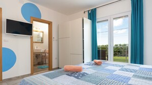 A bedroom with a bed, a TV, a bathroom, and a view of the outdoors. - Villa Comfort with Pool (Kaštelir)