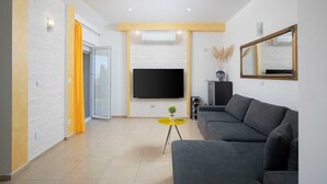 A modern living room with a grey sofa, a flat-screen TV mounted on the wall, and a yellow coffee table. - Villa Comfort with Pool (Kaštelir)