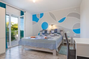A bedroom with a bed, a desk, and a chair. There is a sliding glass door leading to a balcony with a view of greenery. - Villa Comfort with Pool (Kaštelir)