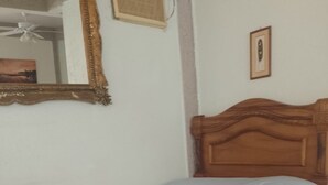 A single bed with a wooden headboard in a room with white walls and a tiled floor. - Walk to beach and many shops in Playas del Coco , Costa Rica (Playas del coco)
