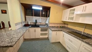 A kitchen with granite countertops, white cabinets, and a tiled floor. - Walk to beach and many shops in Playas del Coco , Costa Rica (Playas del coco)