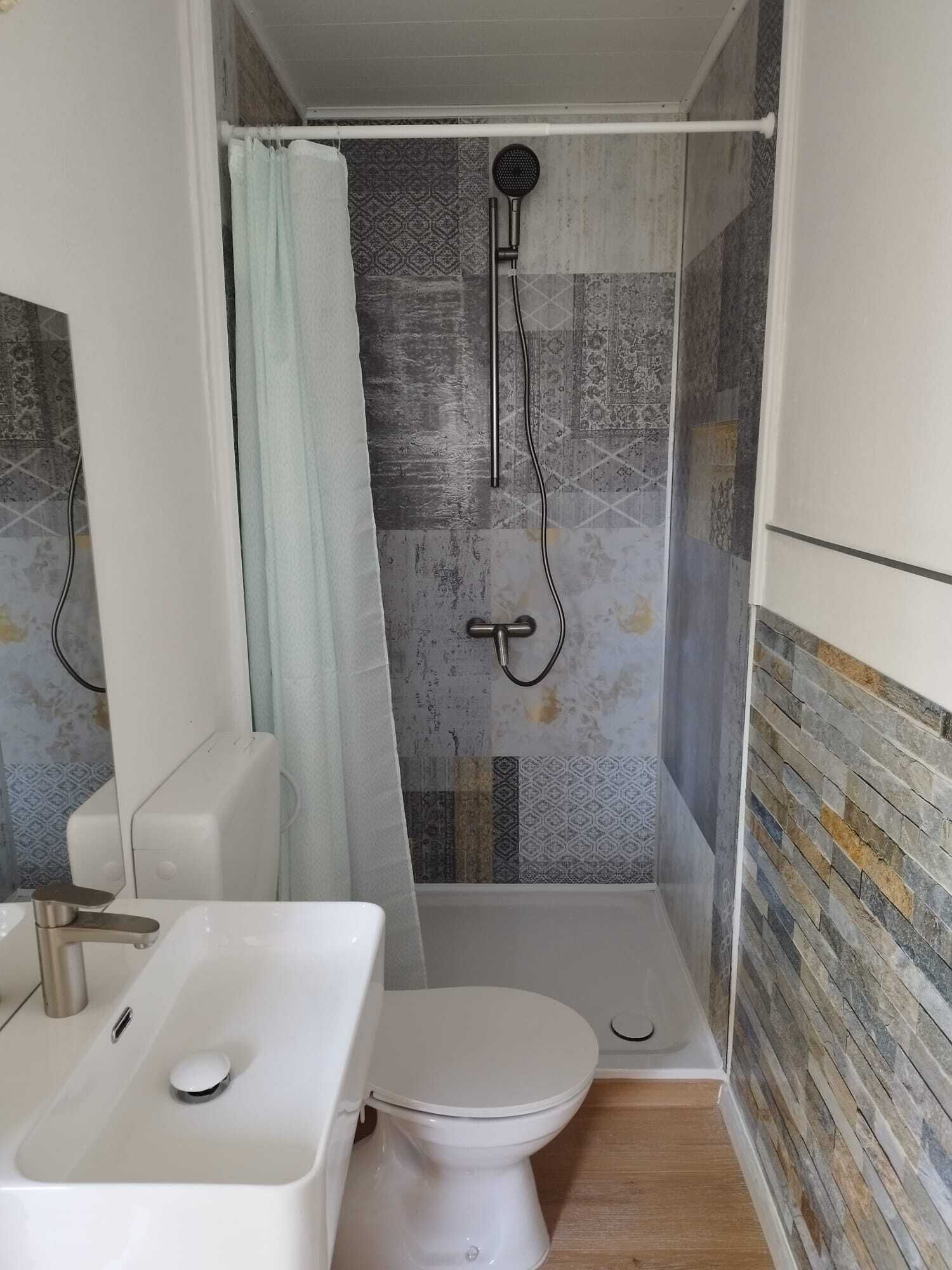 Ein kleines Badezimmer mit Dusche, Toilette und Waschbecken.