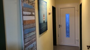 Un couloir avec un lambris en bois, un tableau encadré représentant un phare et une porte dotée d’un panneau en verre dépoli.