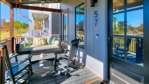A covered porch with a seating area, a door with the number 57, and large windows. - Luxury Carlton Landing Home Golf Cart Included! (Carlton Landing)