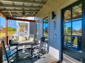 A covered porch with a sofa and chairs, a ceiling fan, and a view of the outside.