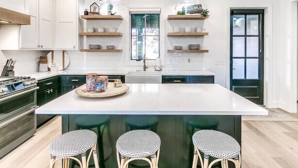 A modern kitchen with white cabinets, a large island, hanging pendant lights, and a window with a view. - Luxury Carlton Landing Home Golf Cart Included! (Carlton Landing)