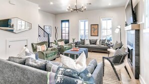 A spacious living room with a fireplace, a large sofa, a coffee table, and a television. - Luxury Carlton Landing Home Golf Cart Included! (Carlton Landing)