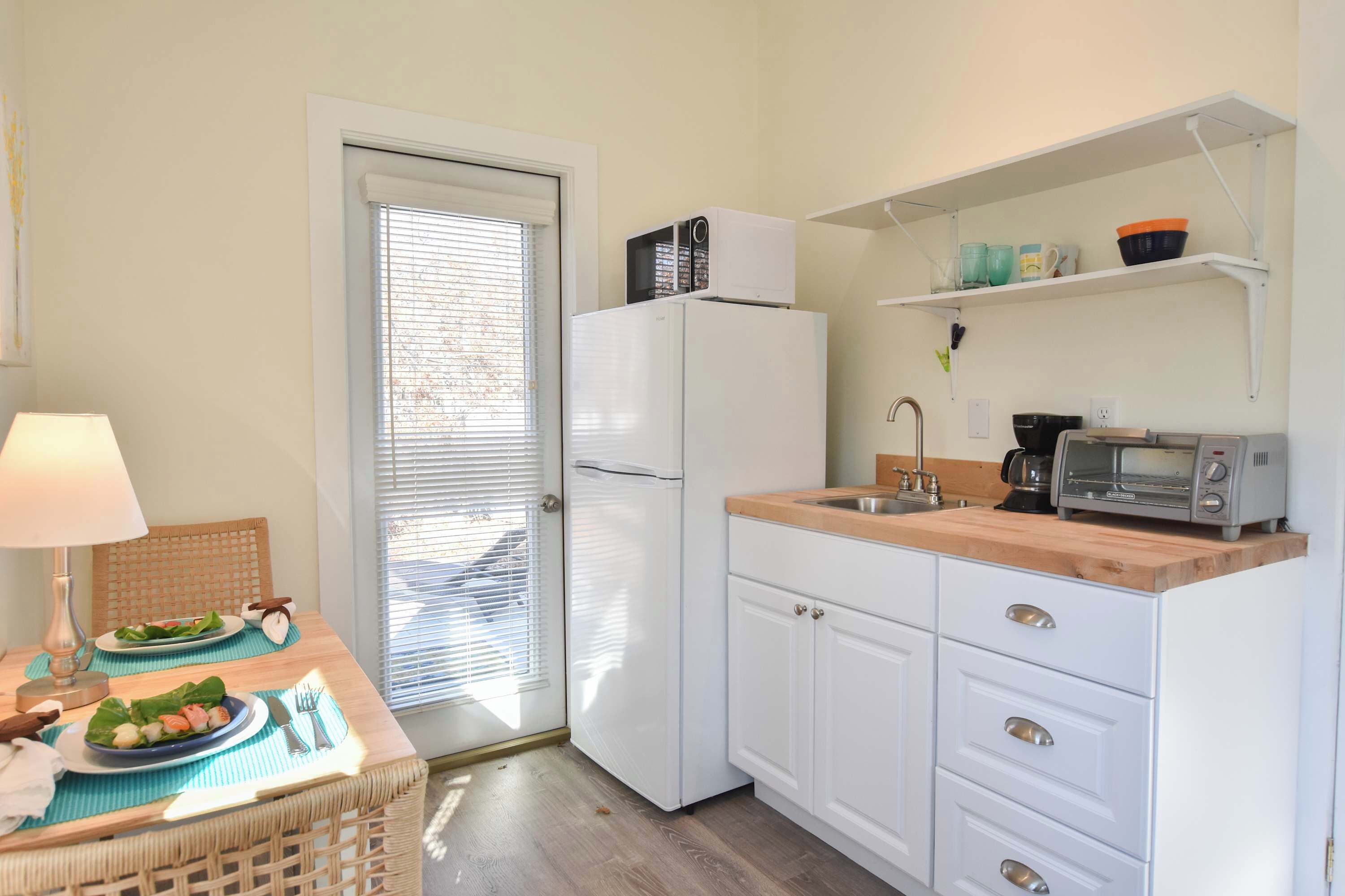 Cocina compacta con refrigerador, microondas, tostadora y una pequeña encimera.