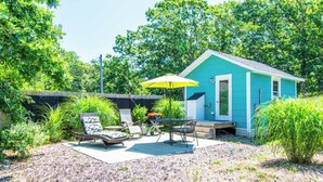 A small blue house with a patio area featuring outdoor furniture and a yellow umbrella. - Cozy Colorful Cottage Perfect for 2! (Eastham)