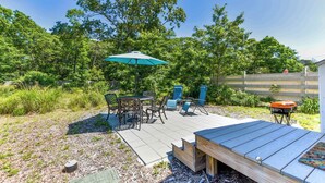 An outdoor patio with a wooden deck, a table with chairs, and a barbecue grill. - Dreamy Cottage for Two! Close to Beaches! (Eastham)