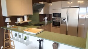 A modern kitchen with stainless steel appliances, a green countertop, and a wooden cutting board. - 3-BEDROOM APARTMENT IN LUXURY RESIDENCE WITH SEA VIEW (Les Trois-Îlets)