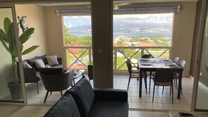 A room with a sofa, dining table, chairs, and a potted plant. - 3-BEDROOM APARTMENT IN LUXURY RESIDENCE WITH SEA VIEW (Les Trois-Îlets)
